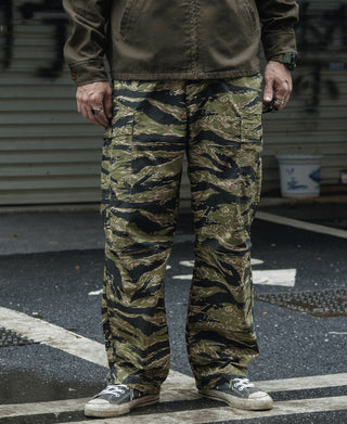 Tiger stripe camo fatigue pants worn with sneakers, full-length view