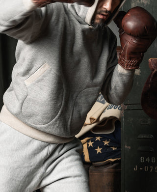 Gray pullover hoodie with hood, kangaroo pocket, and ribbed trim at cuffs and hem.