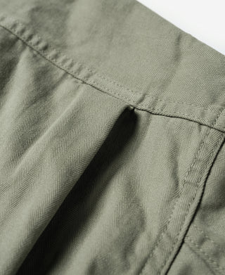 Olive fatigue jacket side seam with pleat and curved pocket edge