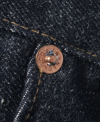 Indigo selvedge denim jeans button and seam detail, copper rivet close-up
