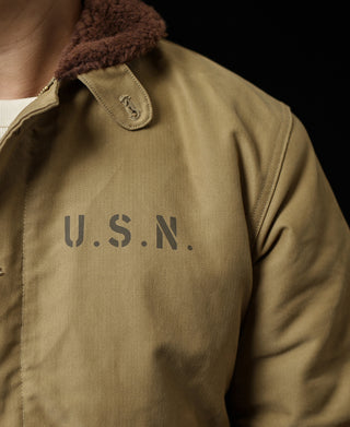 Khaki deck jacket close-up: brown sherpa collar and U.S.N. chest embroidery
