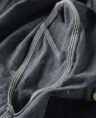 Indigo denim jacket shoulder yoke with contrast-stitched edge and pocket opening