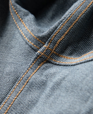 Indigo denim jacket yoke seam with orange-brown double-needle stitching