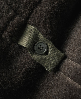 Olive flight jacket cuff with round button and stitched knit trim.