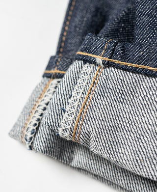 Embroidered interior label on dark blue selvedge denim jeans with orange-brown stitching