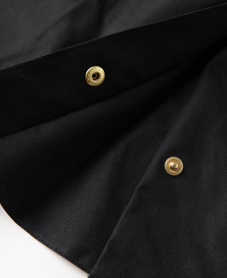 Black waxed chore jacket with brass snap buttons and pleated fabric detail