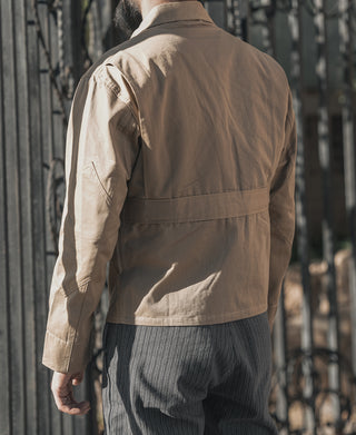 Khaki flight jacket on model, long sleeves, rear yoke, and hem above dark pants