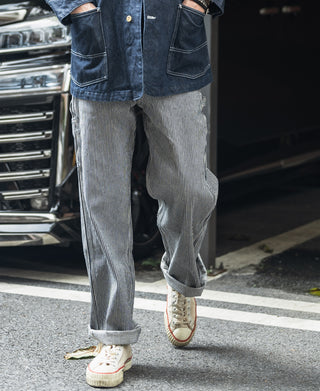 Striped carpenter pants with multiple patch pockets and cuffed hems, worn with sneakers.