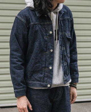 Indigo denim jacket on person with standing collar, front buttons, chest pockets.