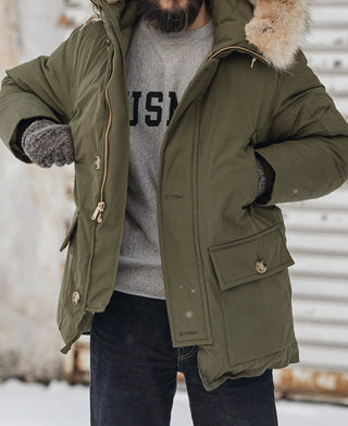 Olive down parka worn with faux-fur hood, front pockets, and drawcord hem