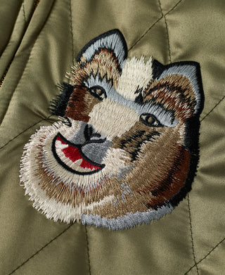 Embroidered smiling animal face patch on olive quilted souvenir jacket