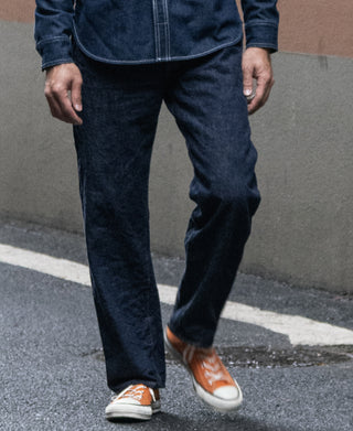 Dark blue denim jeans on model, straight leg with tapered ankle opening
