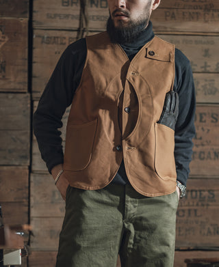 Khaki canvas hunting vest worn over a long-sleeve shirt, chest pocket visible
