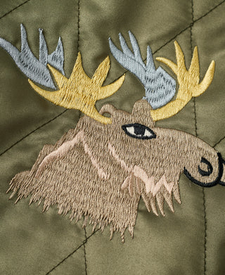 Embroidered moose head patch with gold and blue antlers on olive jacket