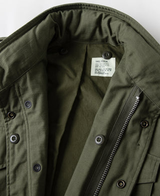 Olive field jacket interior with snap buttons, zipper, and size tag