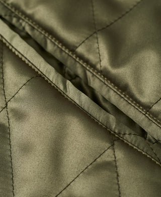 Quilted olive jacket fabric with stitched seam and edge trim