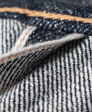 Selvedge denim edge with white yarn line and narrow red stripe