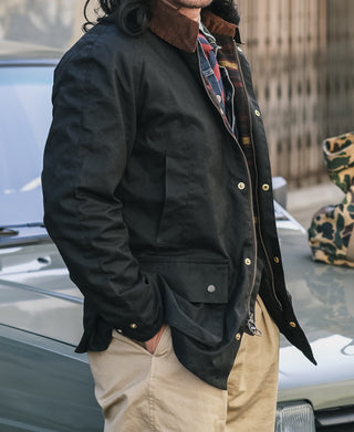 Black waxed chore jacket with button front, chest pockets, and dark hood lining