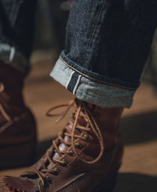 Dark indigo denim jeans cuff with contrast stitching and orange selvedge edge