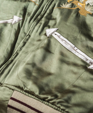 Reversible souvenir jacket in olive green with white-trim pocket and striped trim hem.