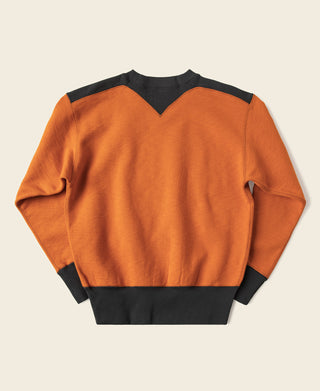 Orange and dark two-tone sweatshirt with V-shaped yoke seam and black cuffs.
