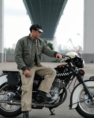 Olive MA-1 flight jacket on model sitting, front zipper and collar detail visible