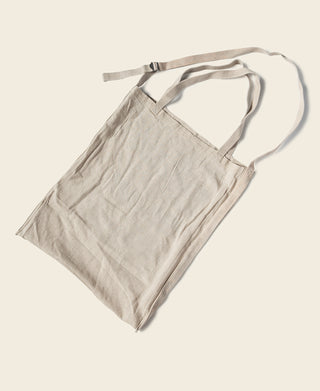 Natural lightweight linen tote bag with short fabric handles and open top.