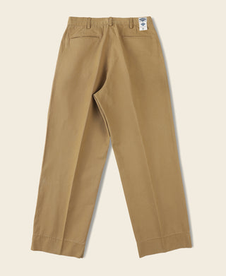 Yellow chino trousers flat lay with front pleats and side pockets; size tag on waistband