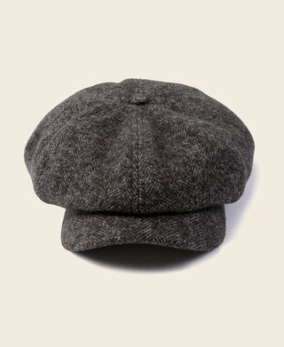 Dark gray herringbone wool newsboy cap with curved brim and side seam detail.