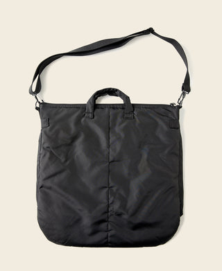 Black nylon helmet bag with top handle, shoulder straps, and front buttoned panel