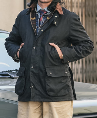 Black waxed chore jacket with utility pockets and button-up front, hood with fur trim