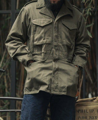 Olive field jacket worn by man, chest flap pockets and button front