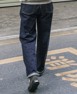 Indigo denim jeans, relaxed straight leg with cuffs and visible front pocket and belt loops.