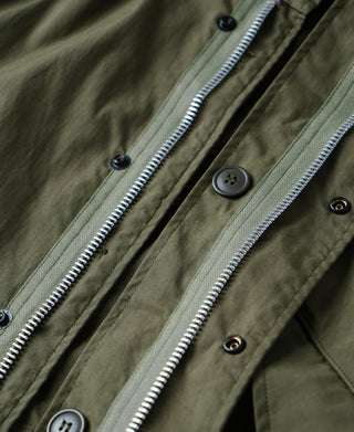 Olive M-65 parka with front zipper and dark buttons at collar placket.