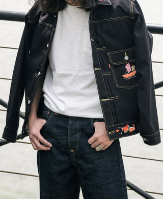 Black tour jacket with embroidered chest pocket and gold trim, worn open