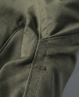 Olive flight jacket shoulder seam with reinforced stitching detail.
