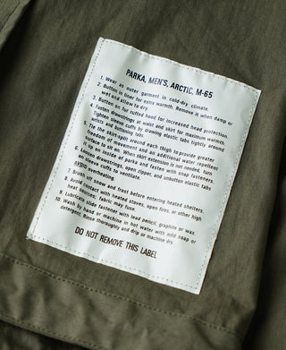 Olive M-65 parka garment label patch on chest panel.