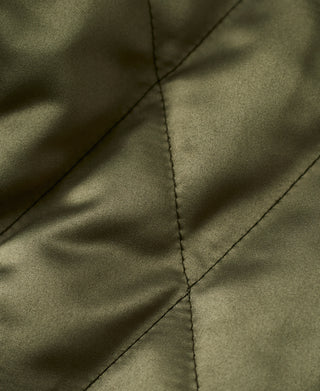 Close-up of olive quilted fabric with diagonal stitching on reversible jacket