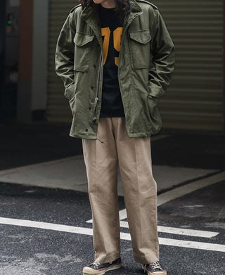 Olive field jacket worn open with button pockets and drawstring hem