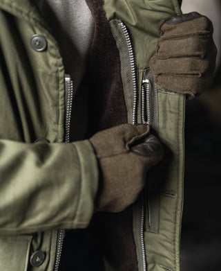 Olive flight jacket front zipper and knit cuff, glove close-up