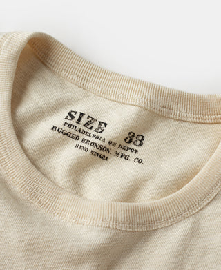 Cream T-shirt neckline close-up with printed size label on the inside collar