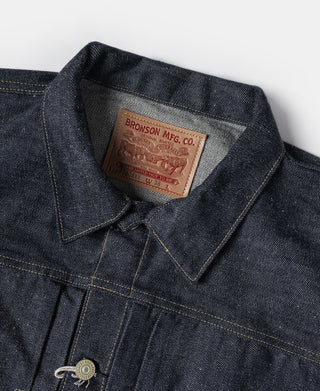 Indigo denim jacket collar with leather brand patch and button placket