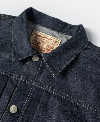 Indigo denim jacket collar with button and interior leather-look brand tag.