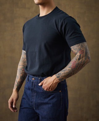 Dark crew-neck cotton T-shirt on model, side view showing short sleeve and hem