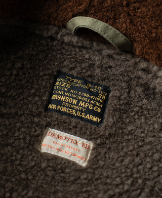 Brown shearling lining label patch on olive flight jacket collar interior