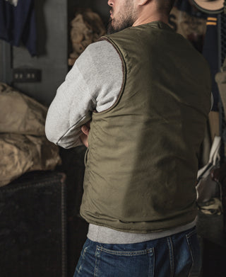 Olive pile-lined vest with side patch pocket and gray sleeve cuffs