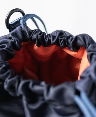Navy chalk bag top opening with orange interior liner and gathered drawstring
