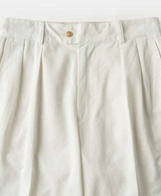 White pleated trouser front with button closure and fly seam detail.