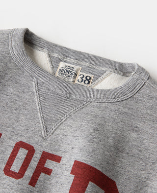 Gray V-neck sweater neckline with brand label and red “OF” graphic detail