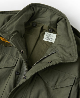 Olive M-65 field jacket with buttoned flap pockets and inner label